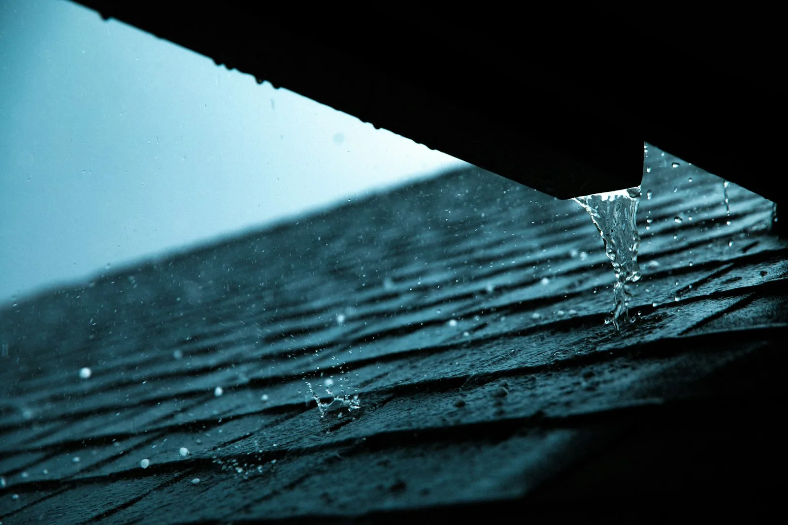 Rainwater spilling from a roof edge during heavy rain